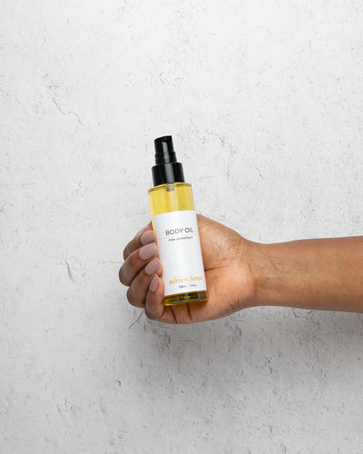 Body oil being held in a woman's hand to show scale/size comparison