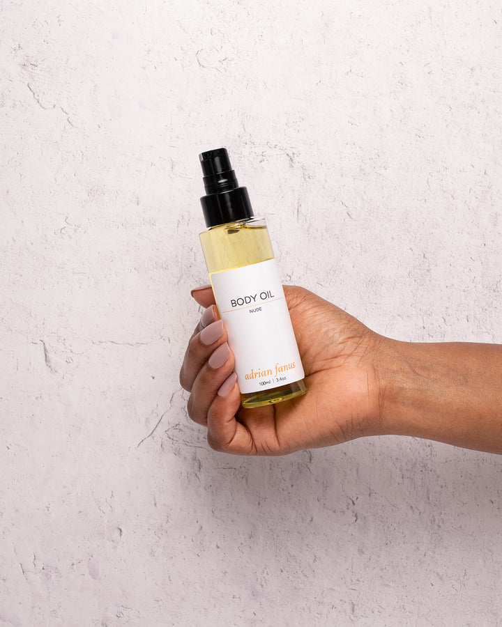 Body oil being held in hands to show scale. 